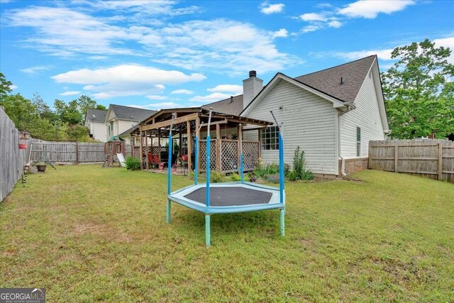 rear view of house featuring a yard and a trampoline