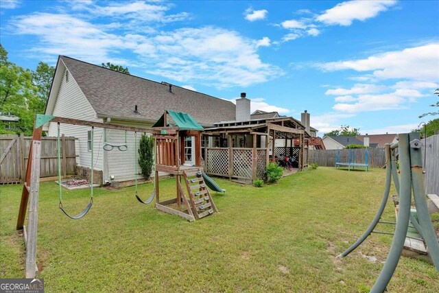 rear view of house with a playground, a trampoline, and a lawn