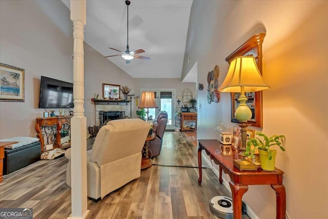 living room with decorative columns, hardwood / wood-style flooring, high vaulted ceiling, and ceiling fan