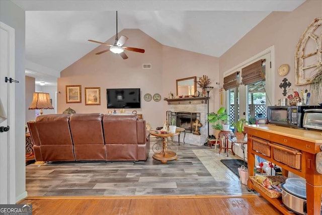 living room with light hardwood / wood-style flooring, high vaulted ceiling, and ceiling fan