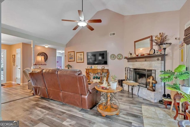 living room featuring ceiling fan, high vaulted ceiling, wood-type flooring, and a fireplace