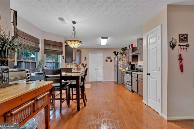 dining room with a textured ceiling and light wood-type flooring