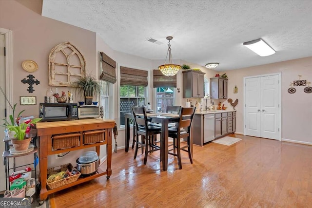 dining space with light hardwood / wood-style floors, a textured ceiling, and sink