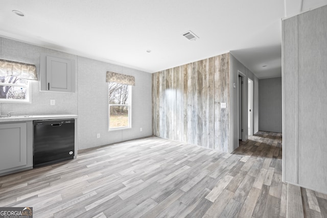 kitchen featuring gray cabinets, dishwasher, and light wood-type flooring