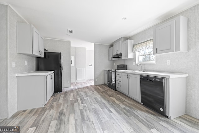 kitchen featuring white cabinetry, sink, light wood-type flooring, and black appliances