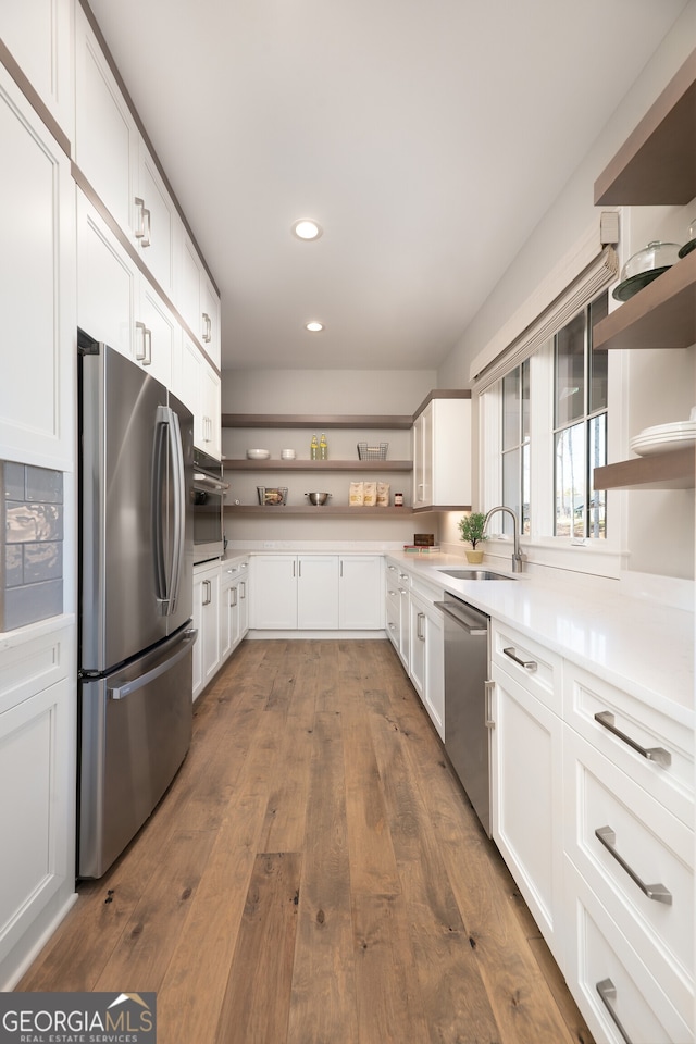 kitchen with appliances with stainless steel finishes, sink, dark hardwood / wood-style floors, and white cabinets