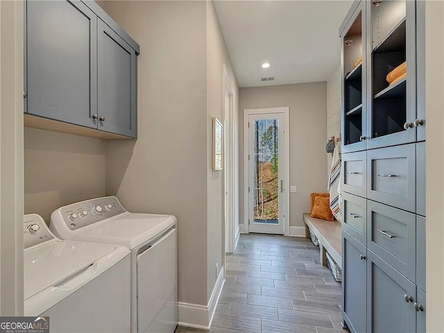 laundry room featuring hardwood / wood-style floors, washer and dryer, and cabinets