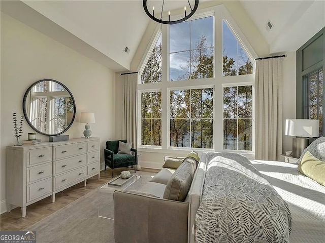 bedroom with light hardwood / wood-style flooring, a chandelier, and high vaulted ceiling