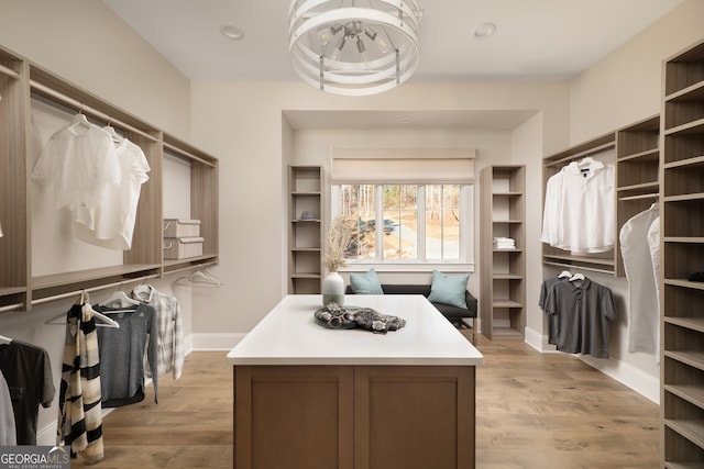 spacious closet featuring light hardwood / wood-style flooring and a notable chandelier