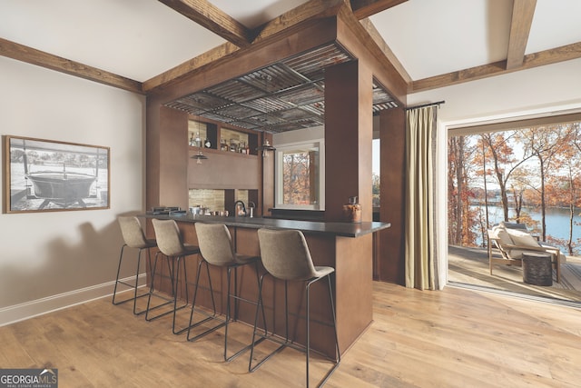 kitchen with light hardwood / wood-style floors, kitchen peninsula, a water view, and a breakfast bar