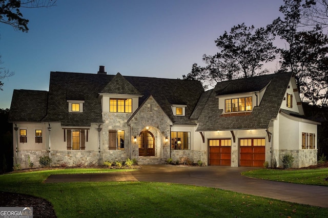 french provincial home featuring a yard and a garage