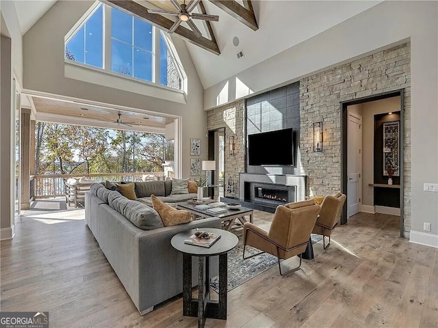 living room with a wealth of natural light, beam ceiling, light hardwood / wood-style flooring, and high vaulted ceiling