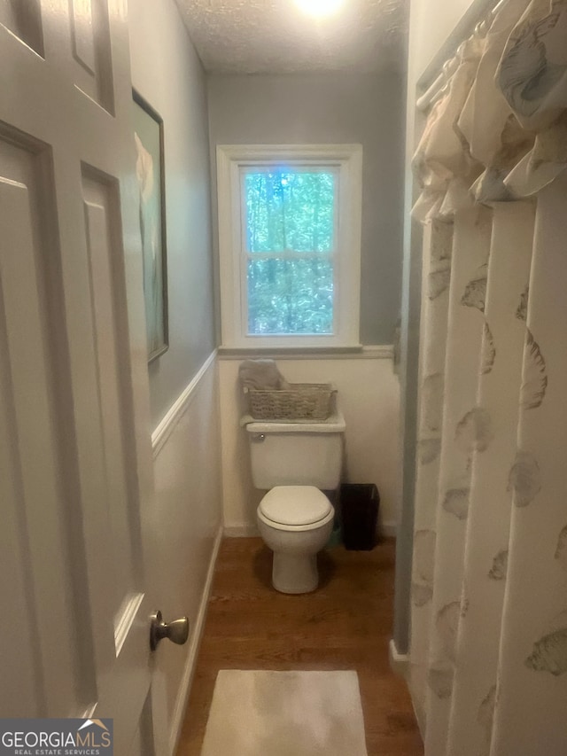 bathroom with toilet, a textured ceiling, and hardwood / wood-style floors