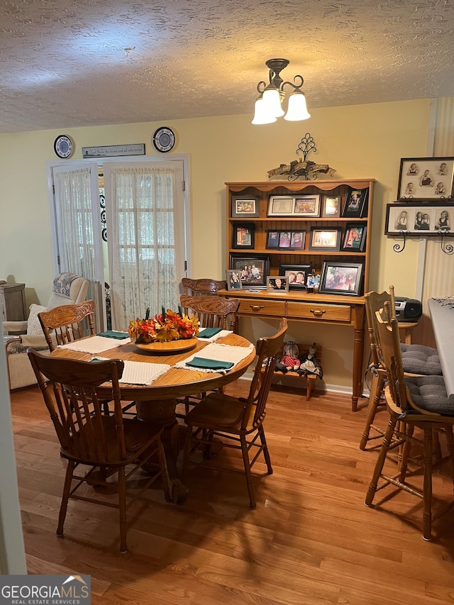 dining room featuring a notable chandelier, hardwood / wood-style floors, and a textured ceiling