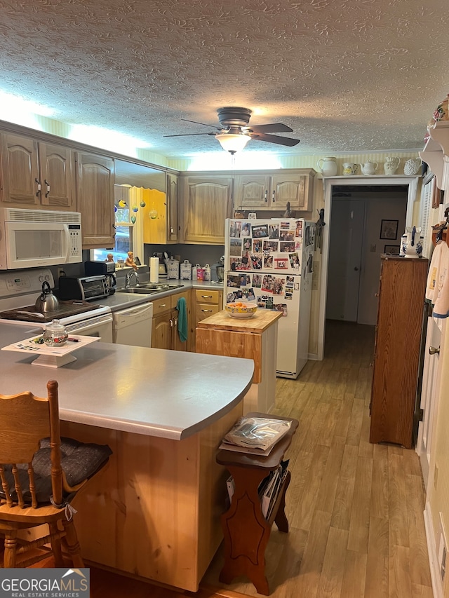 kitchen featuring white appliances, light wood-type flooring, a textured ceiling, kitchen peninsula, and ceiling fan