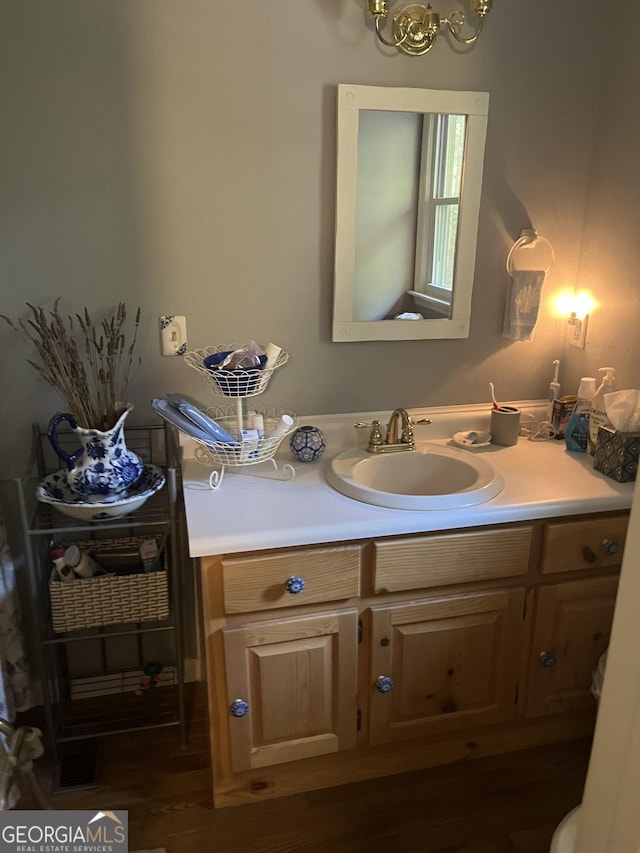 bathroom with an inviting chandelier, wood finished floors, and vanity