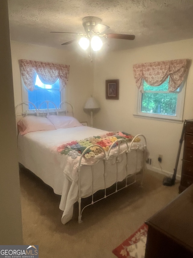 bedroom with a textured ceiling, carpet flooring, and ceiling fan