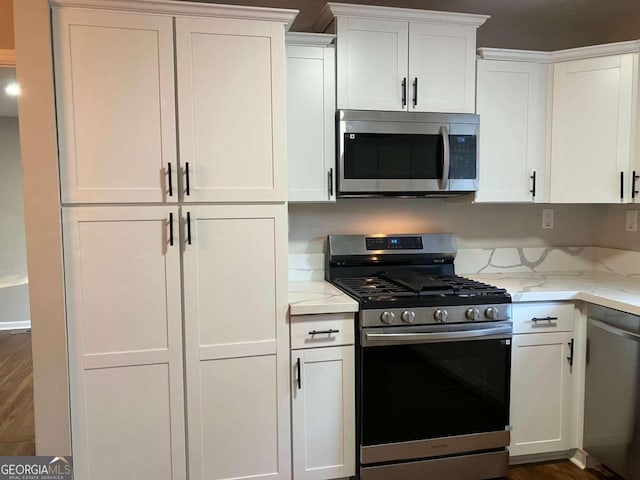 kitchen featuring white cabinetry, light stone countertops, appliances with stainless steel finishes, and dark wood-type flooring