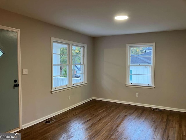 spare room with dark wood-type flooring and a wealth of natural light