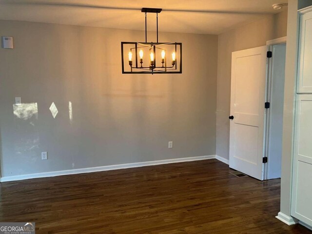 unfurnished room featuring dark wood-type flooring and a chandelier