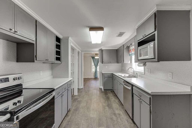 kitchen with light hardwood / wood-style flooring, sink, crown molding, gray cabinets, and appliances with stainless steel finishes