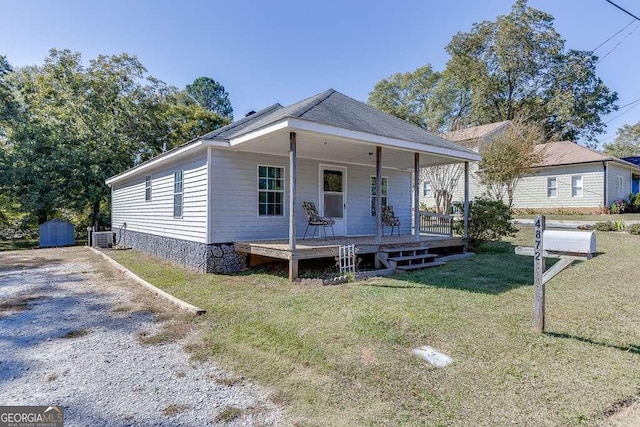 view of front of home with covered porch, a front yard, a shed, and central AC unit