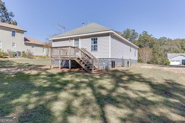 rear view of house featuring a wooden deck and a yard