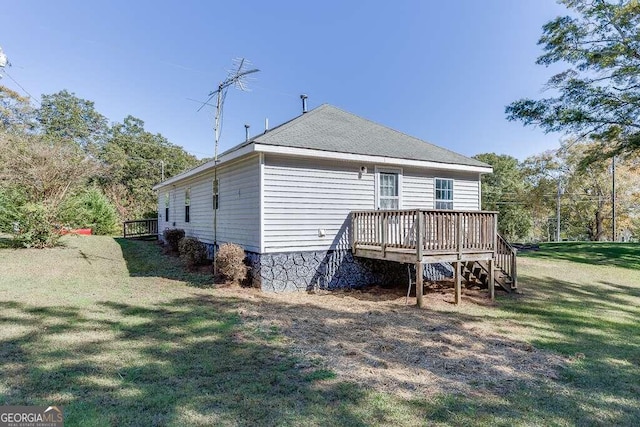 rear view of property featuring a wooden deck and a lawn