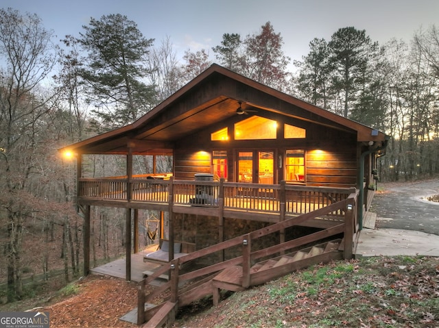 property exterior at dusk featuring a patio, a deck, and ceiling fan