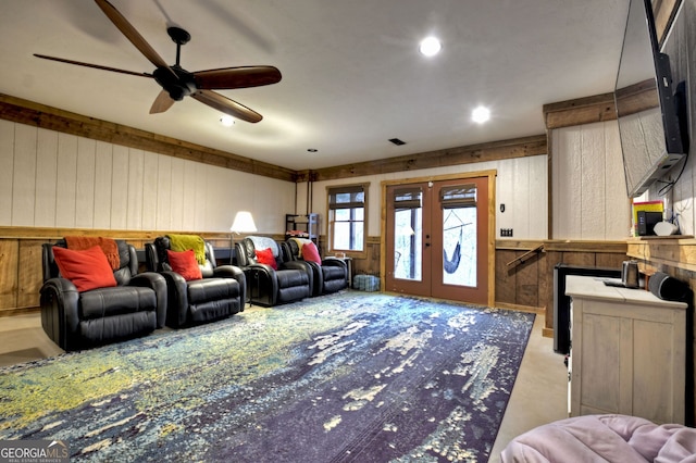 living room with french doors, ceiling fan, and wood walls