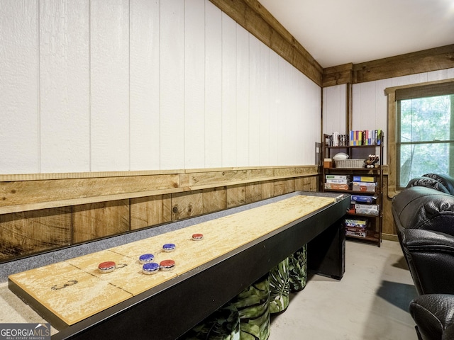 playroom featuring concrete flooring and wooden walls