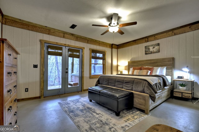 bedroom featuring access to exterior, ceiling fan, french doors, concrete flooring, and wooden walls