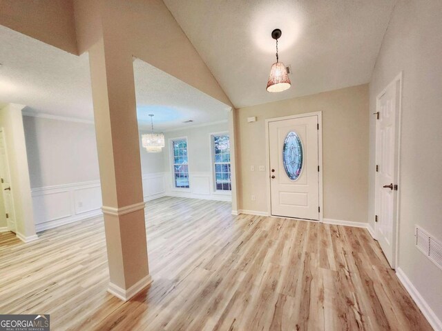 foyer with a textured ceiling, vaulted ceiling, and light wood-type flooring