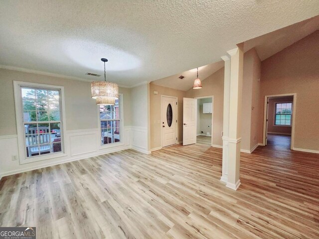 unfurnished dining area featuring light hardwood / wood-style flooring, crown molding, ornate columns, and vaulted ceiling