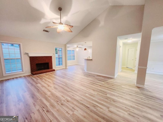 unfurnished living room featuring light hardwood / wood-style flooring, a healthy amount of sunlight, high vaulted ceiling, and a fireplace