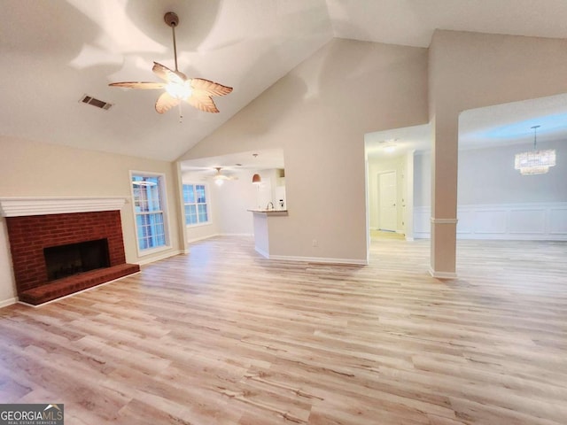 unfurnished living room with light hardwood / wood-style flooring, a fireplace, high vaulted ceiling, and ceiling fan