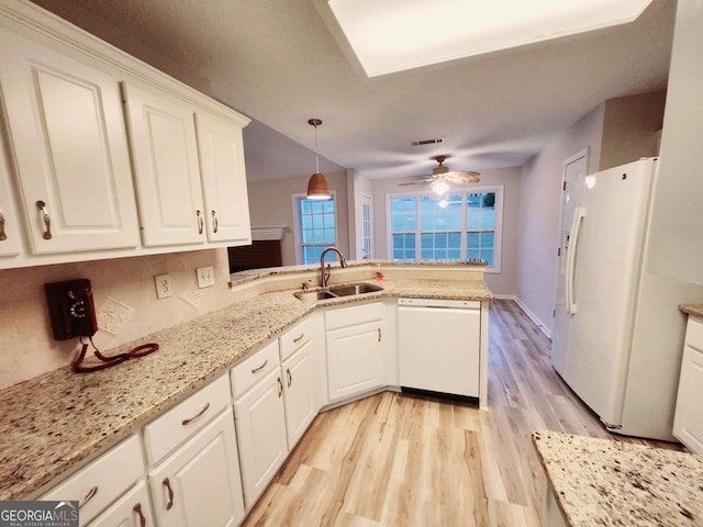 kitchen featuring white appliances, sink, kitchen peninsula, pendant lighting, and white cabinets