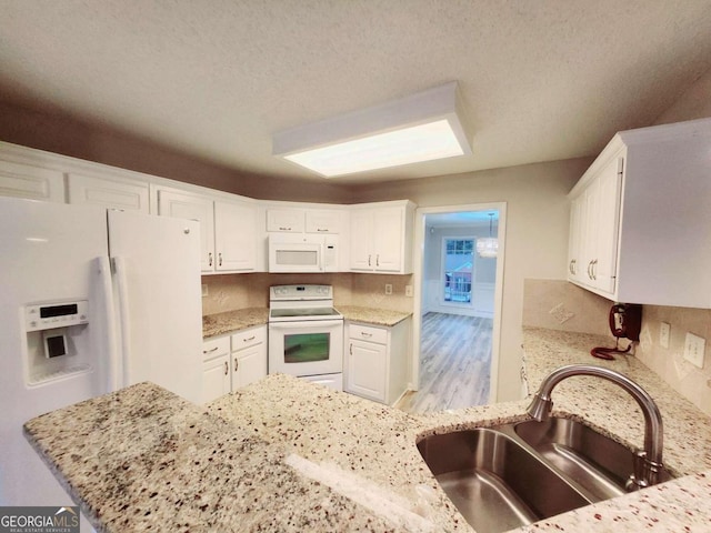 kitchen featuring white cabinetry, light stone countertops, light hardwood / wood-style floors, sink, and white appliances