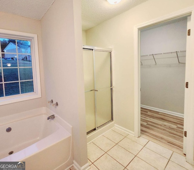 bathroom with separate shower and tub, hardwood / wood-style floors, and a textured ceiling