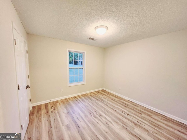 spare room with light hardwood / wood-style floors and a textured ceiling