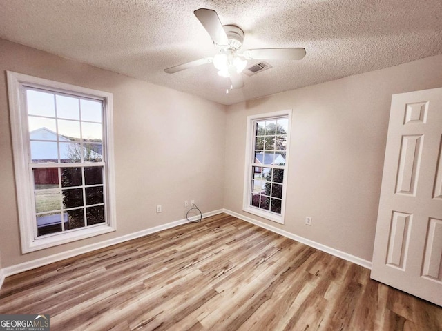 empty room with a textured ceiling, light wood-type flooring, and ceiling fan