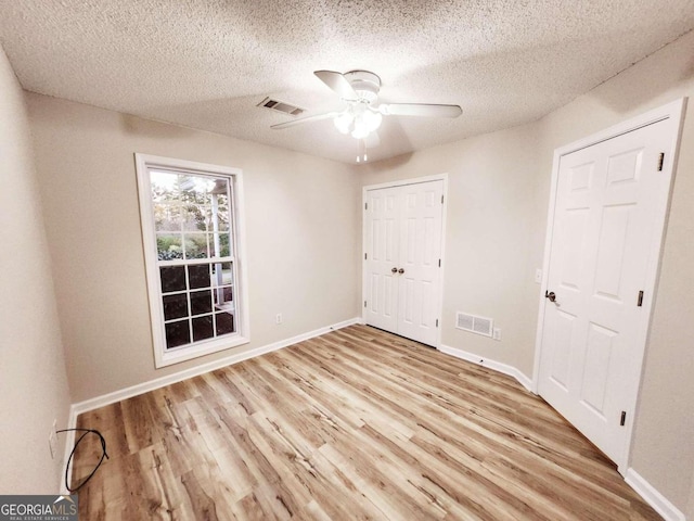 unfurnished bedroom featuring a textured ceiling, light wood-type flooring, and ceiling fan