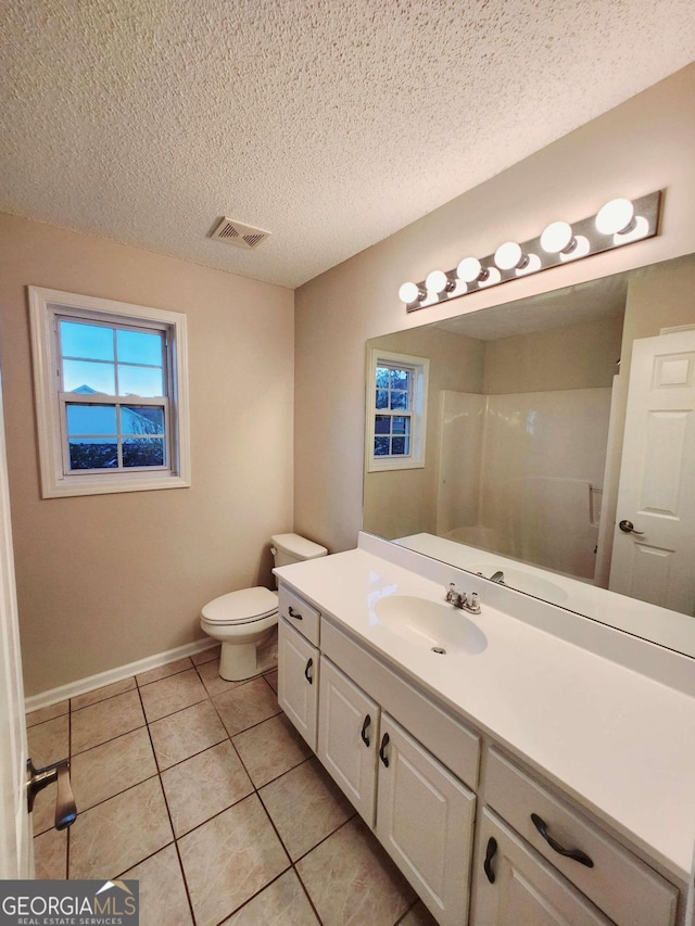 bathroom with a textured ceiling, a shower, toilet, vanity, and tile patterned flooring