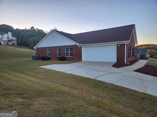 view of front of property with central air condition unit, a garage, and a lawn