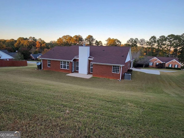 back house at dusk with a patio and a lawn