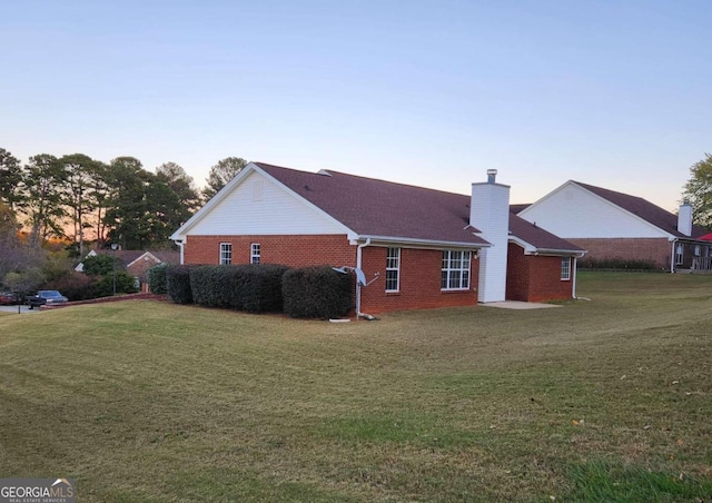 property exterior at dusk featuring a yard