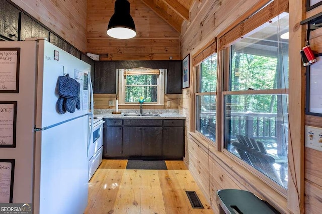 kitchen featuring vaulted ceiling with beams, dark brown cabinetry, white fridge, and sink