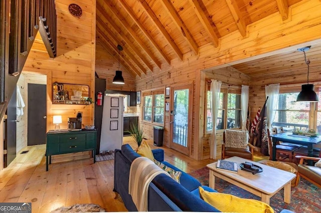 living area featuring beamed ceiling, wood walls, light wood-style flooring, wooden ceiling, and high vaulted ceiling