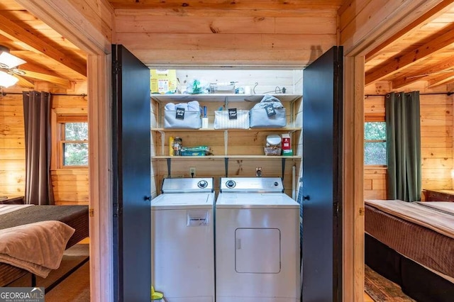 washroom with wooden walls, a healthy amount of sunlight, laundry area, and washing machine and clothes dryer