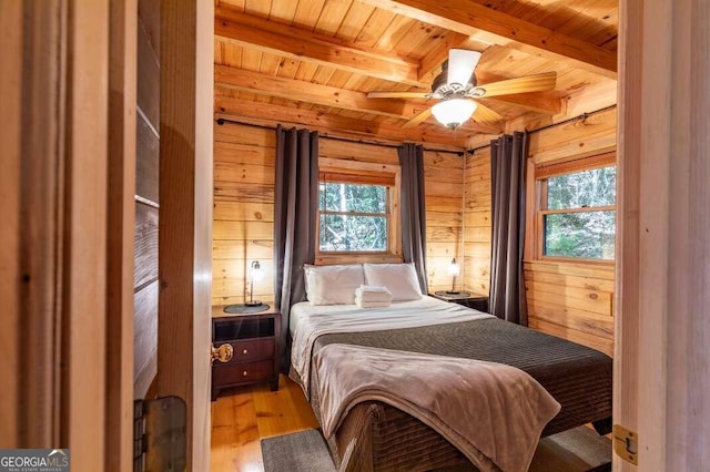 bedroom featuring beam ceiling, wood walls, and wooden ceiling